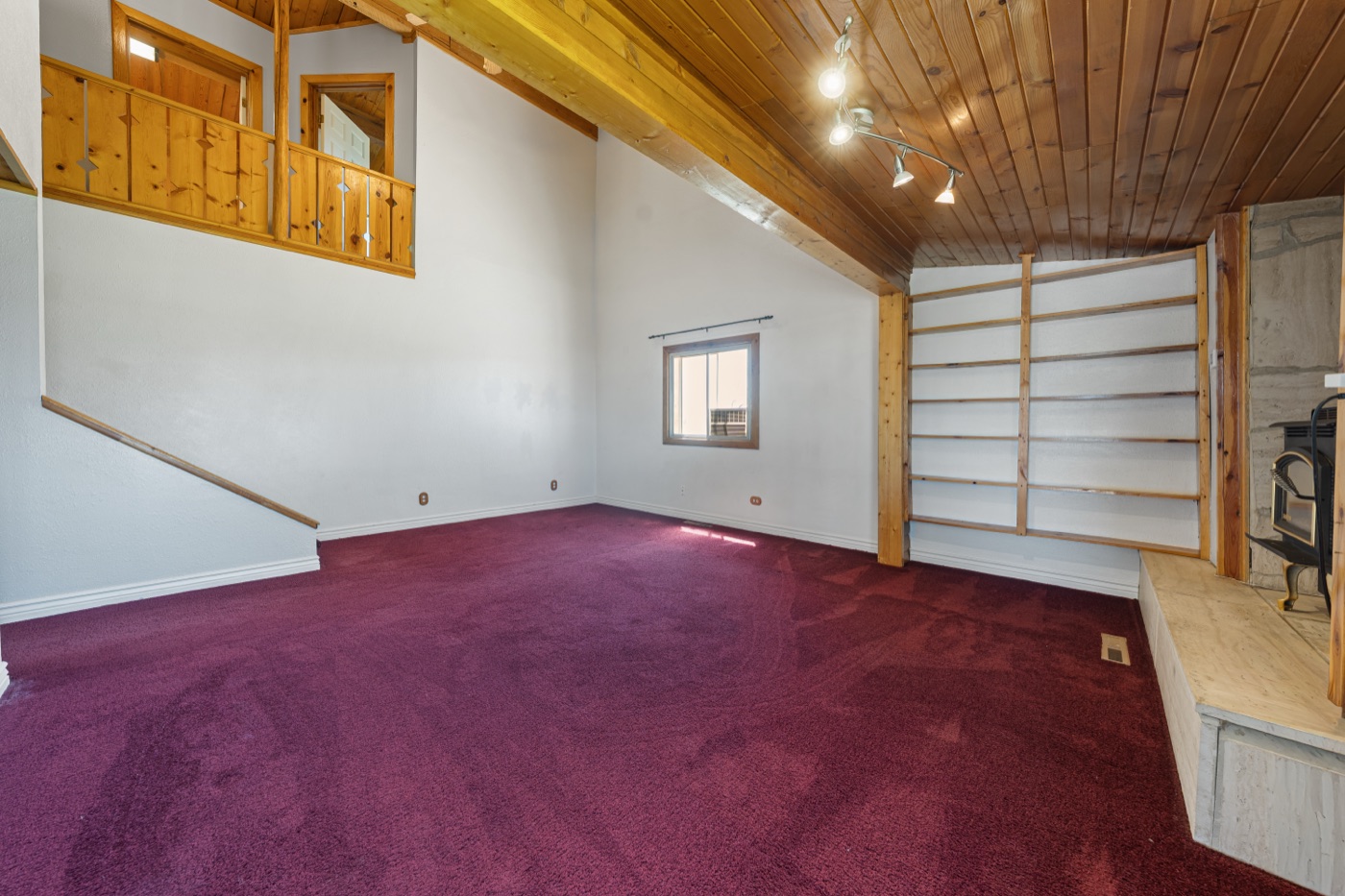 Great room with vaulted wood ceiling, beams, and wood-burning stove