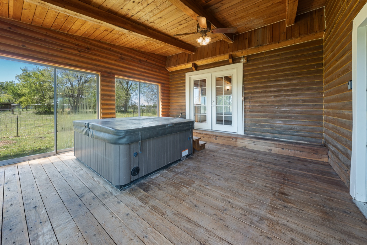 Hot tub on enclosed back patio with log walls